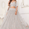 Close-up shot of the exquisite white thread embroidery on the lehenga fabric, adding a touch of e...
