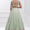 Dupatta flows beautifully in the wind as a woman wears the pastel green lehenga choli set for a t...